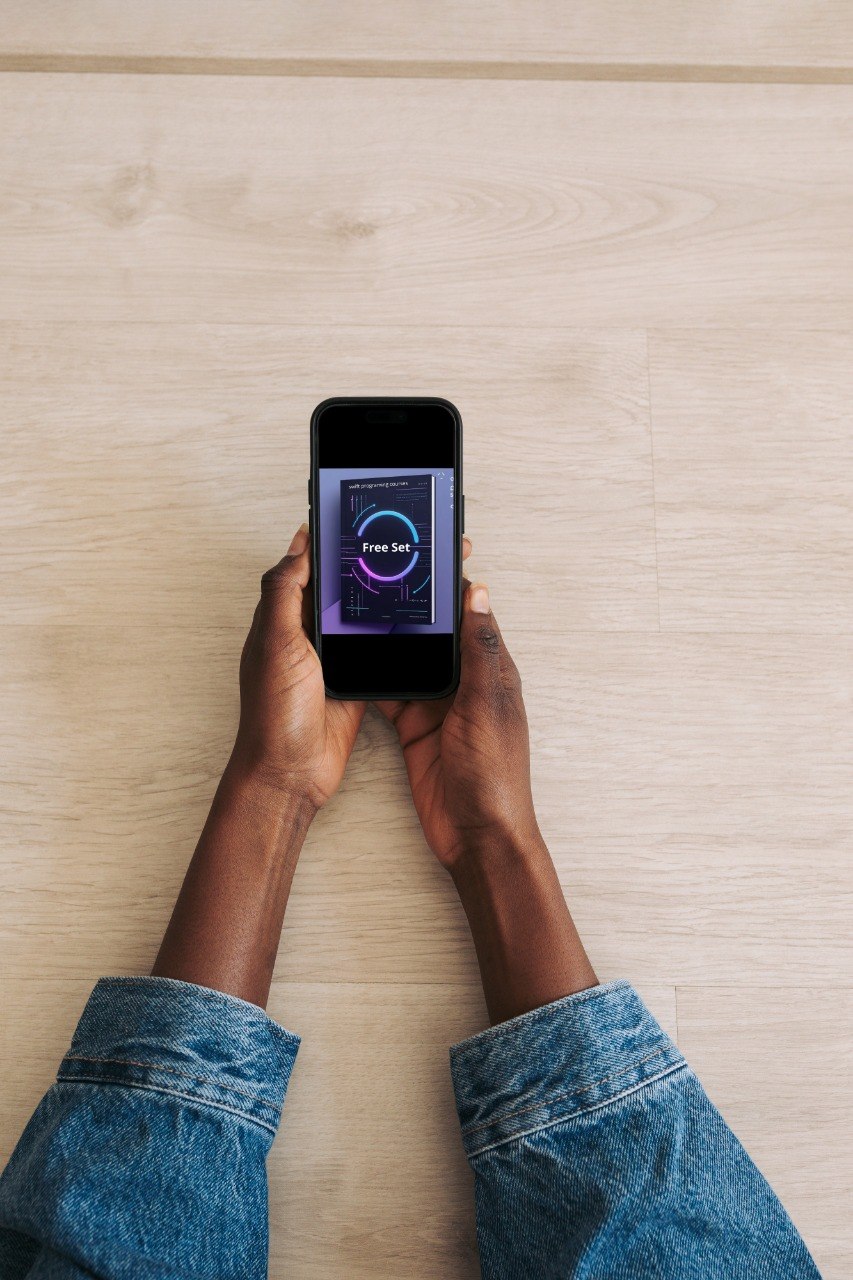 Person holding a smartphone with a music app on a wooden surface
